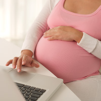 Pregnant woman on her computer.